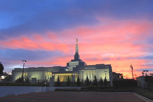 A yellow, pink, and purple sunset behind the illuminated Perth Australia Temple.