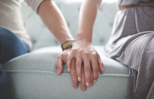 man and woman holding hands while sitting on couch