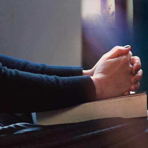 folded hands resting on a book