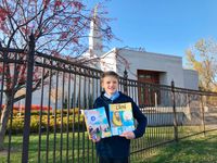 boy holding copies of French Friend in front of temple