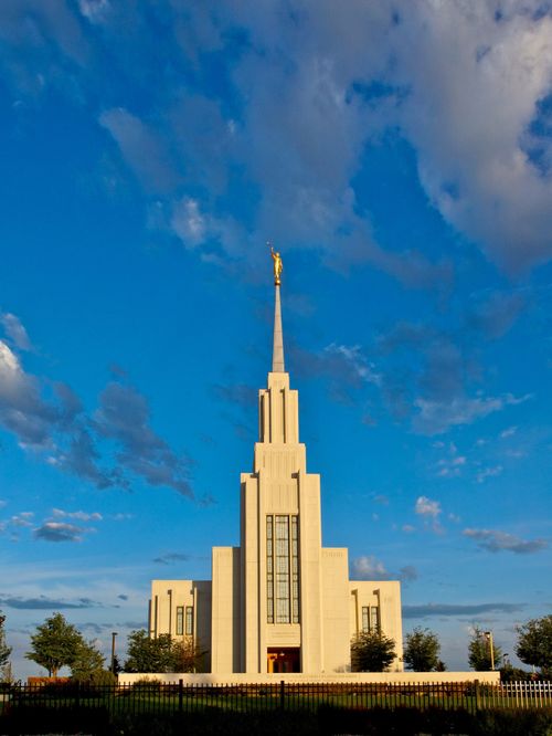A front view of the Twin Falls Idaho Temple, with the fence surrounding the grounds and trees.