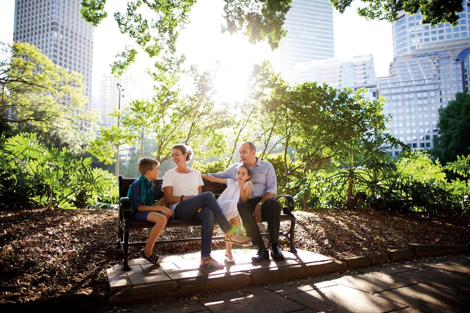 A family in Australia sits together on a park bench.