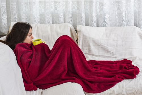 Woman on couch under blanket