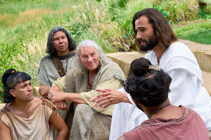 The resurrected Savior, Jesus Christ, appears to his 12 Disciples in the Ancient Americas. They are all seated together on stone steps outdoors. He instructs them on the proper name of His Church and teaches them his Gospel.