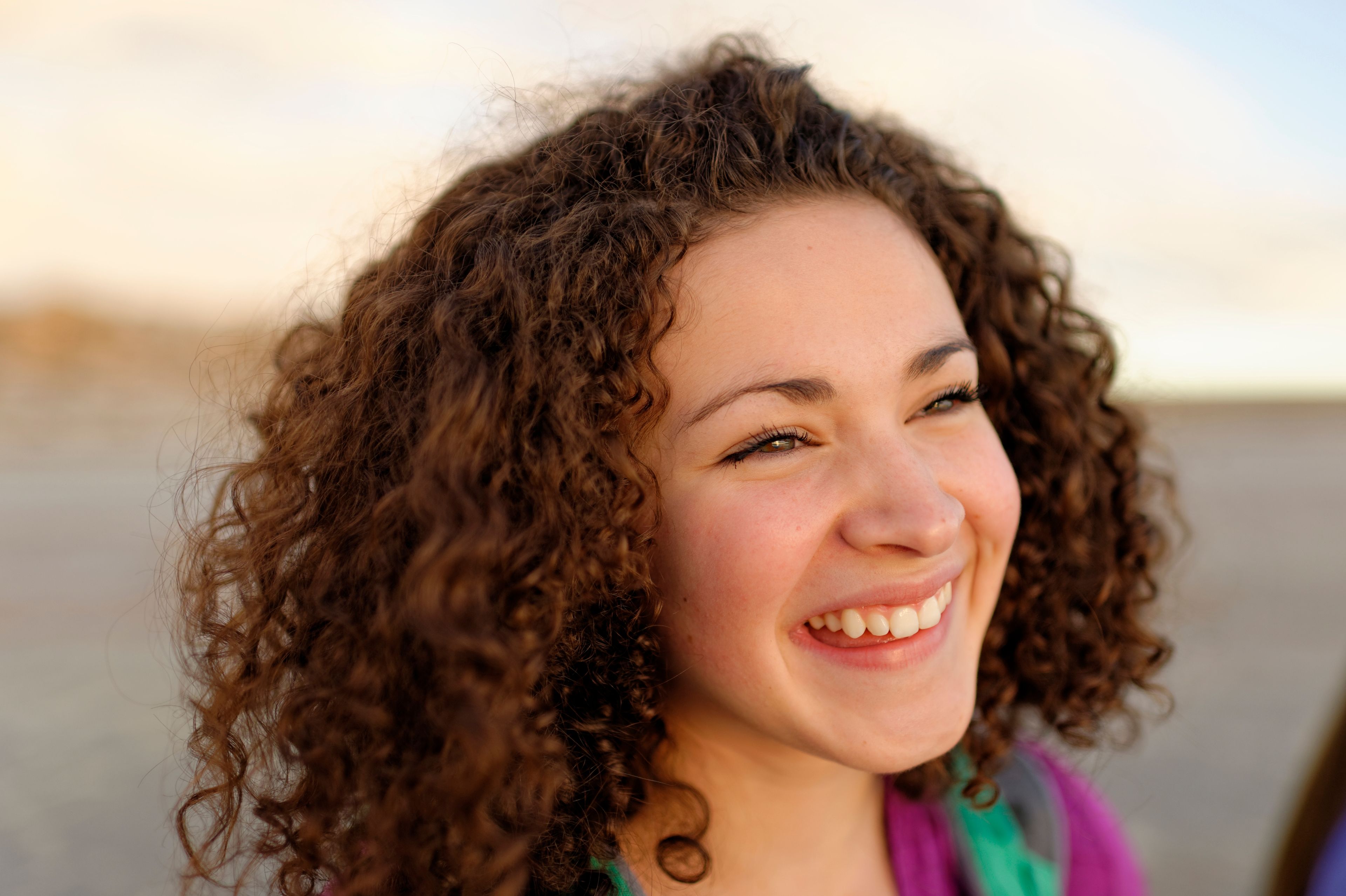 A portrait of a young woman with short curly hair, smiling.