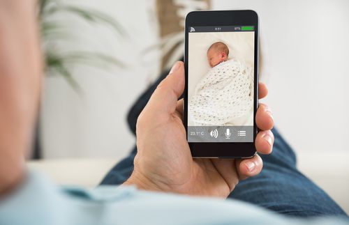 father holding a phone with the image of a sleeping baby