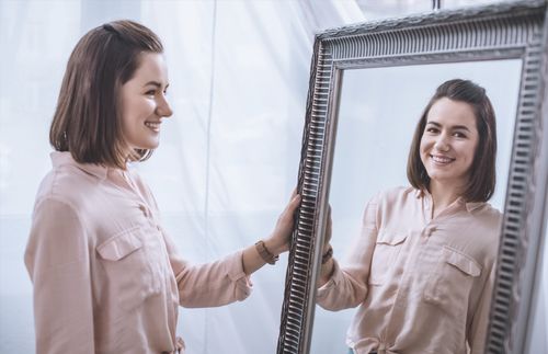 young adult woman looking in a mirror