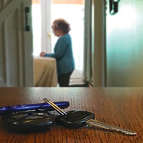a set of keys on a table, with a woman praying in the background