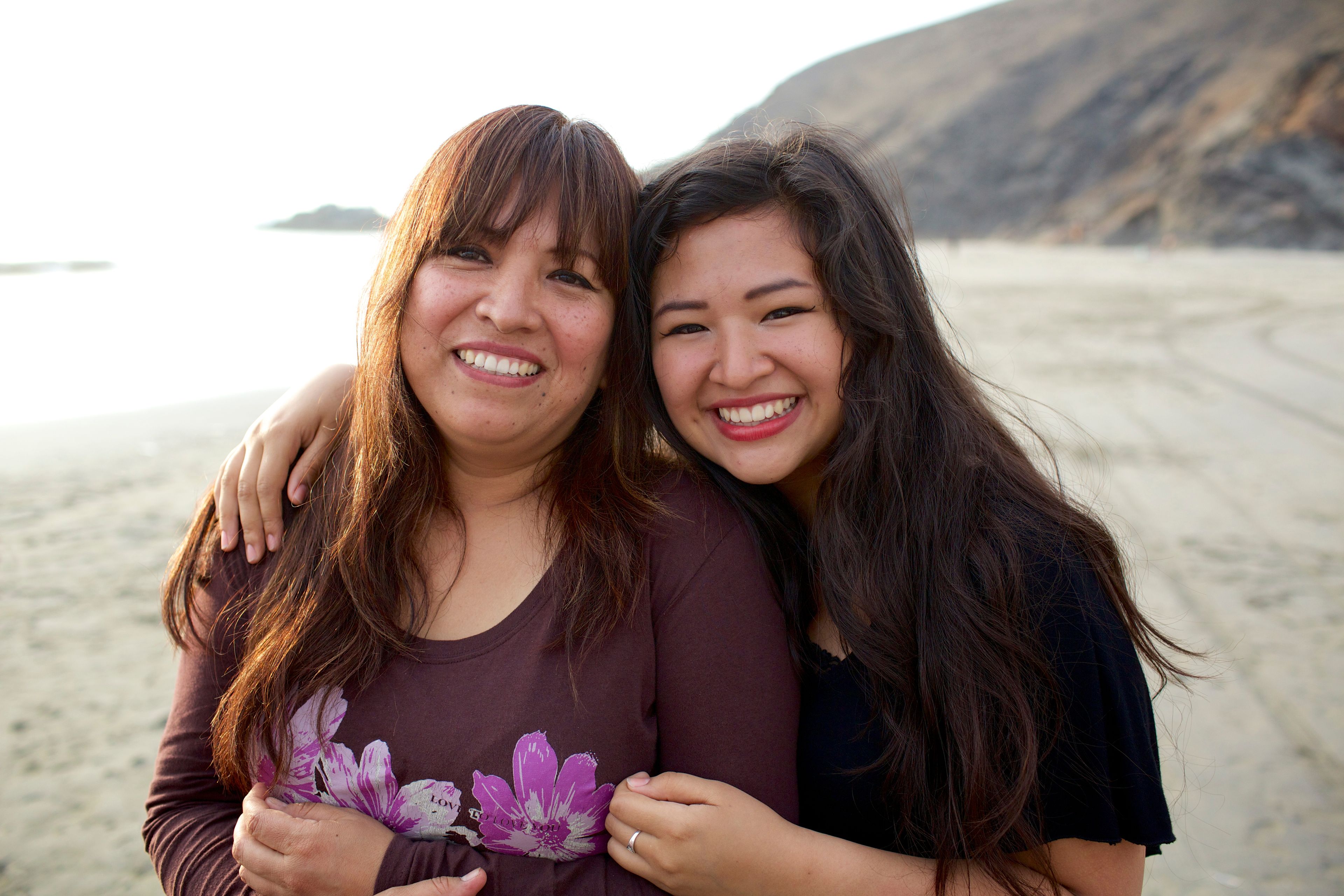A mother poses with her daughter on the beach.