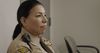 A prison guard stands near inmates who are in a meeting. 