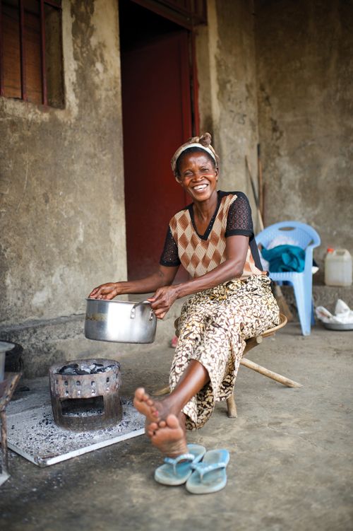 A woman cooking outdoors in a large silver pot.