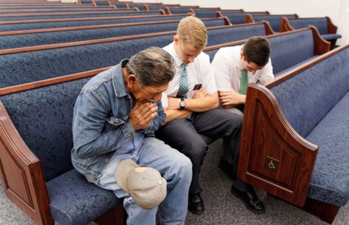 man and missionaries praying in a chapel