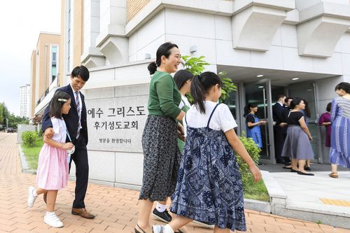 various people walk by a Church sign in Korean