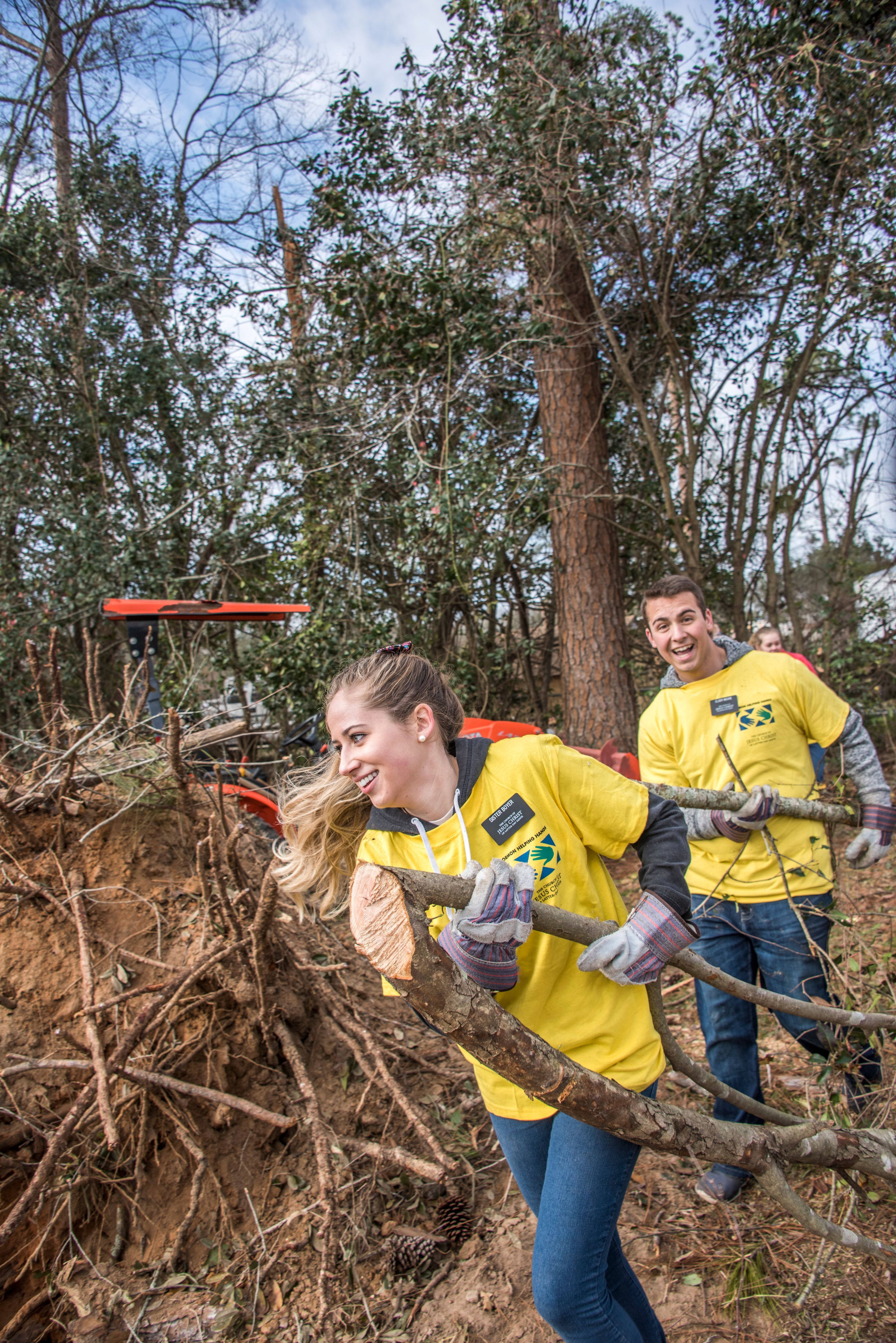 Two missionaries helping to clear away parts of fallen trees after a tornado.