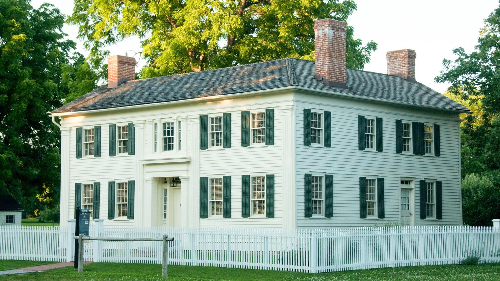 Two-story white house with dark green shutters.