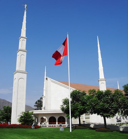 The front side of the Lima Peru Temple on a sunny day, with the Peruvian flag on the temple grounds.