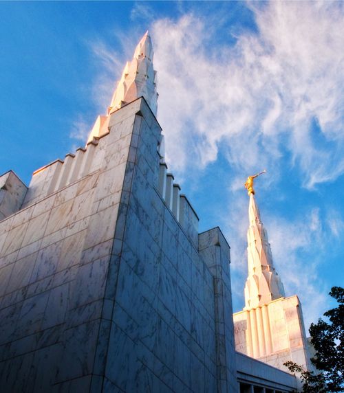 Two of the spires on the Portland Oregon Temple set against a blue sky, with the angel Moroni statue on top of the spire on the right.