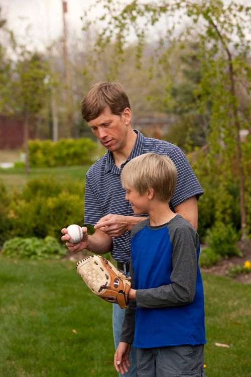 bărbat şi băiat cu o minge de baseball