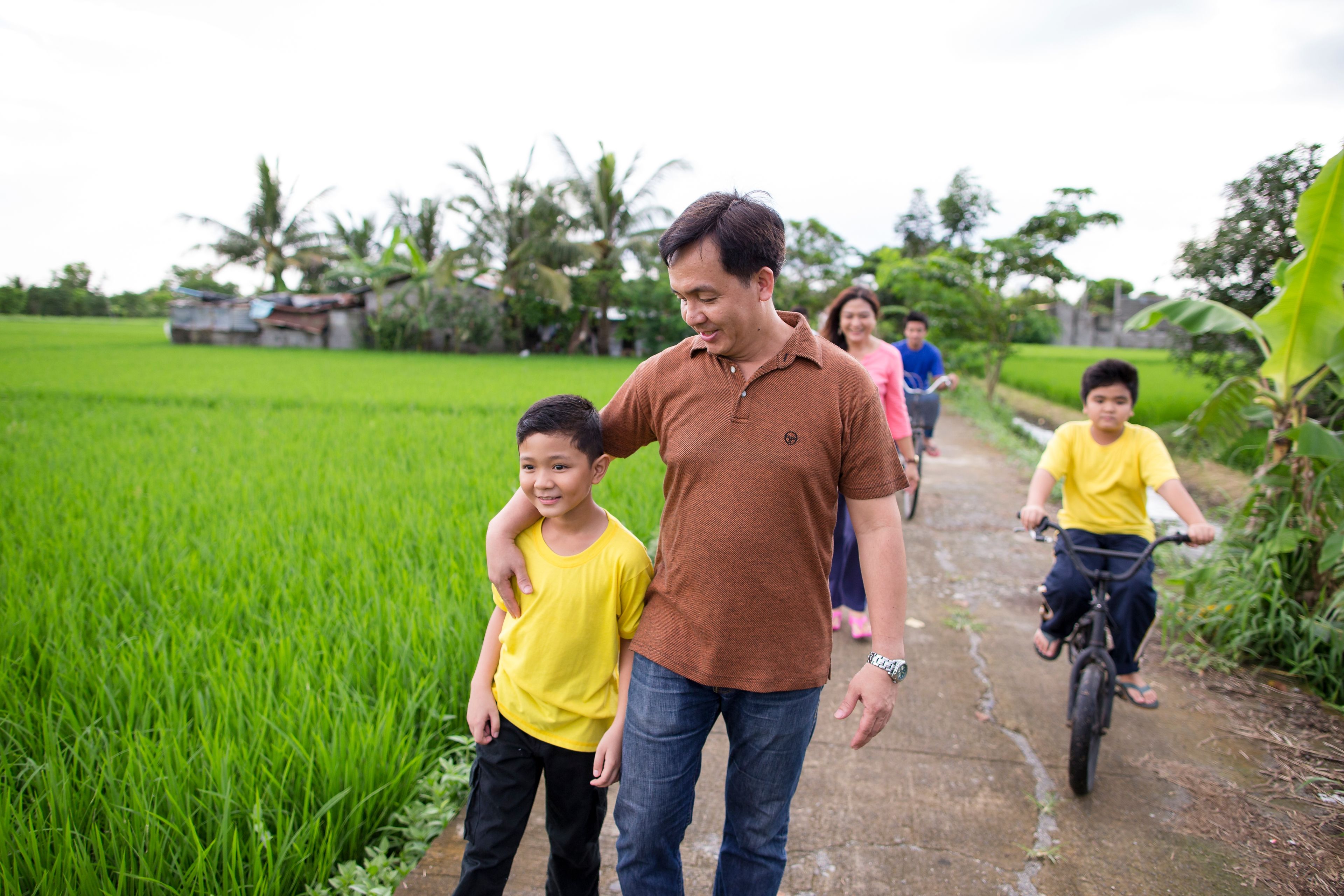 A father goes for a walk through a field with his family.