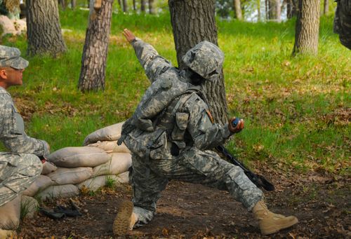 Army soldier in camouflage uniform, throwing grenade in training exercise.  (horiz)