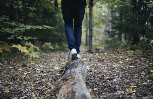 man walking in the forest on a log