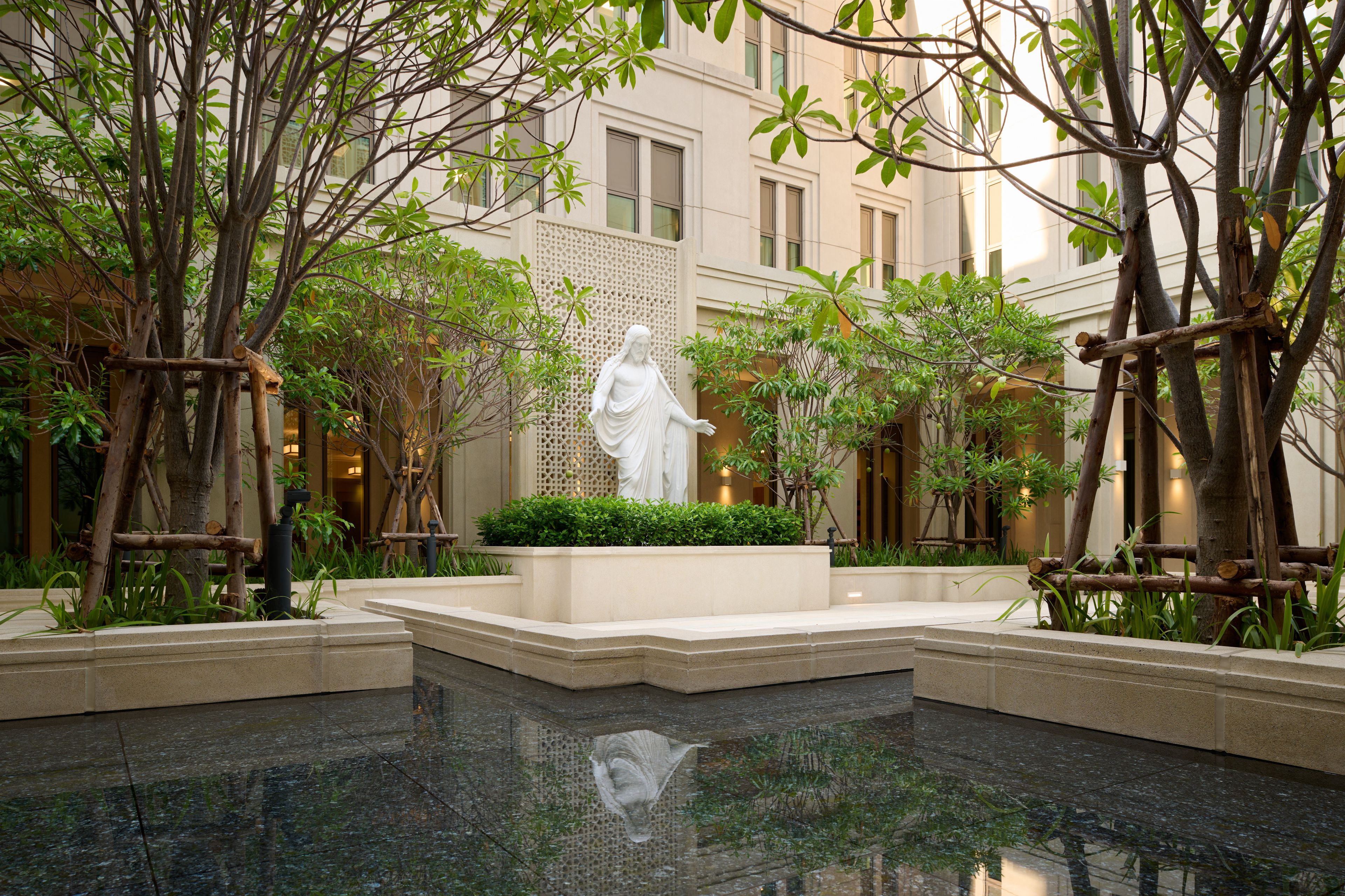 Images of the exterior of the Bangkok Thailand Temple. Images feature the architectural detail of the courtyard with a reflecting pong and Christus statue. 