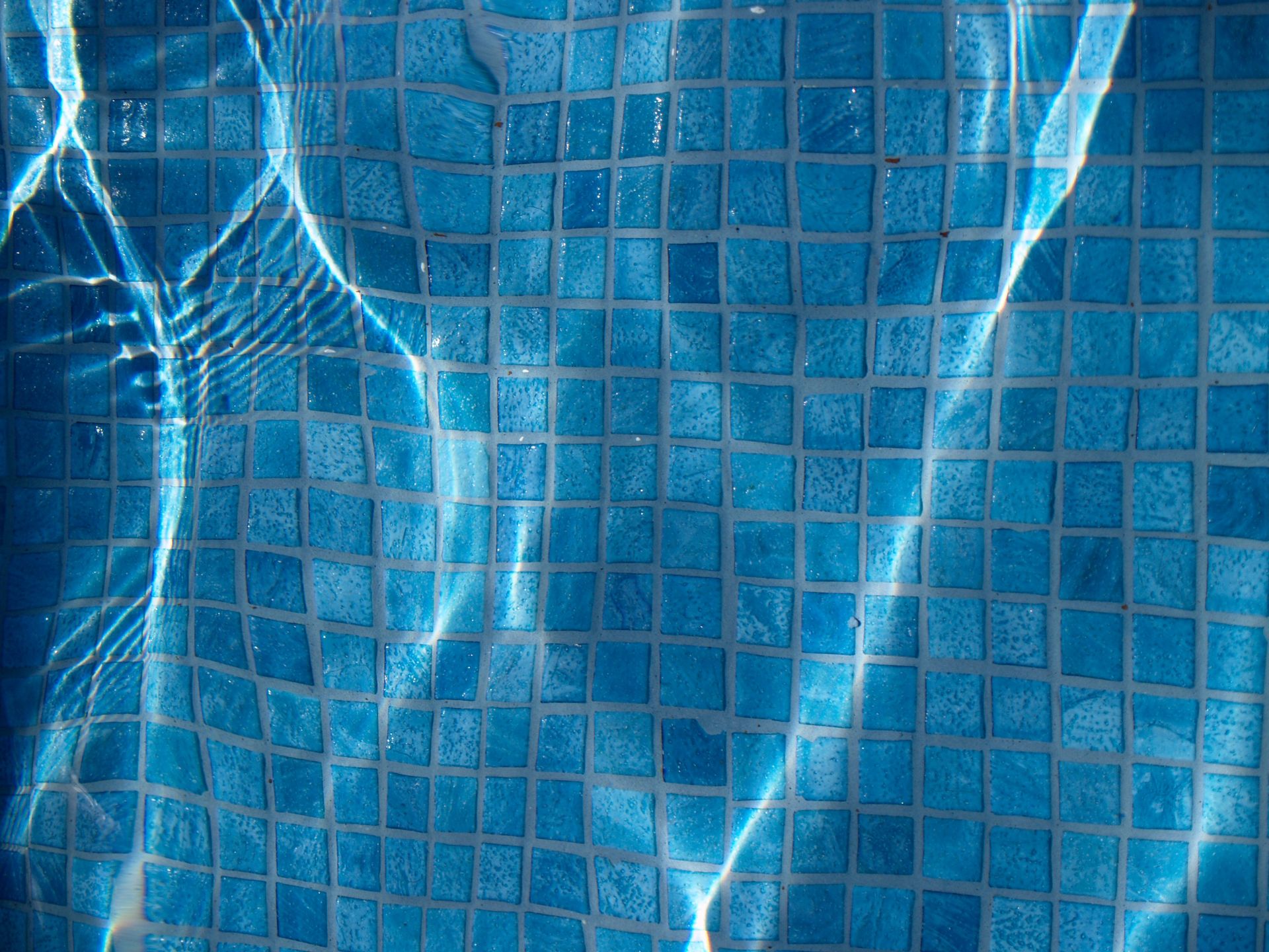 Water reflecting on blue tiles at the bottom of a pool.