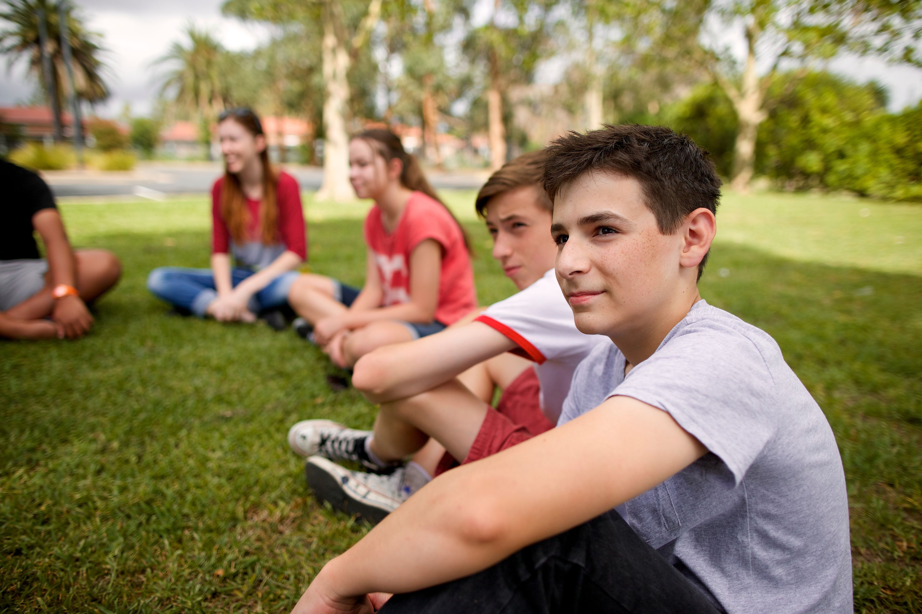 A group of youth sitting outside in a circle.  