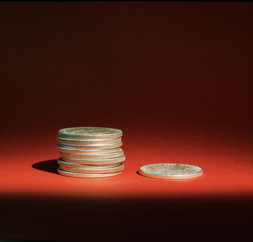 Nine coins in a stack with the tenth coin lying next to them. Illustrates the principle of tithing.