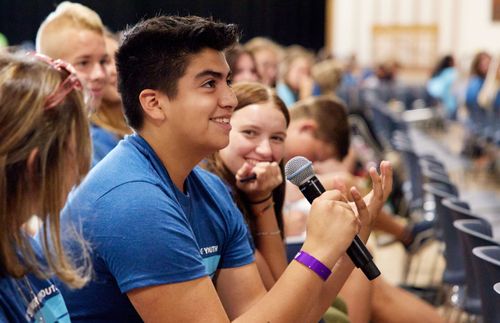 young man holding a microphone in a class