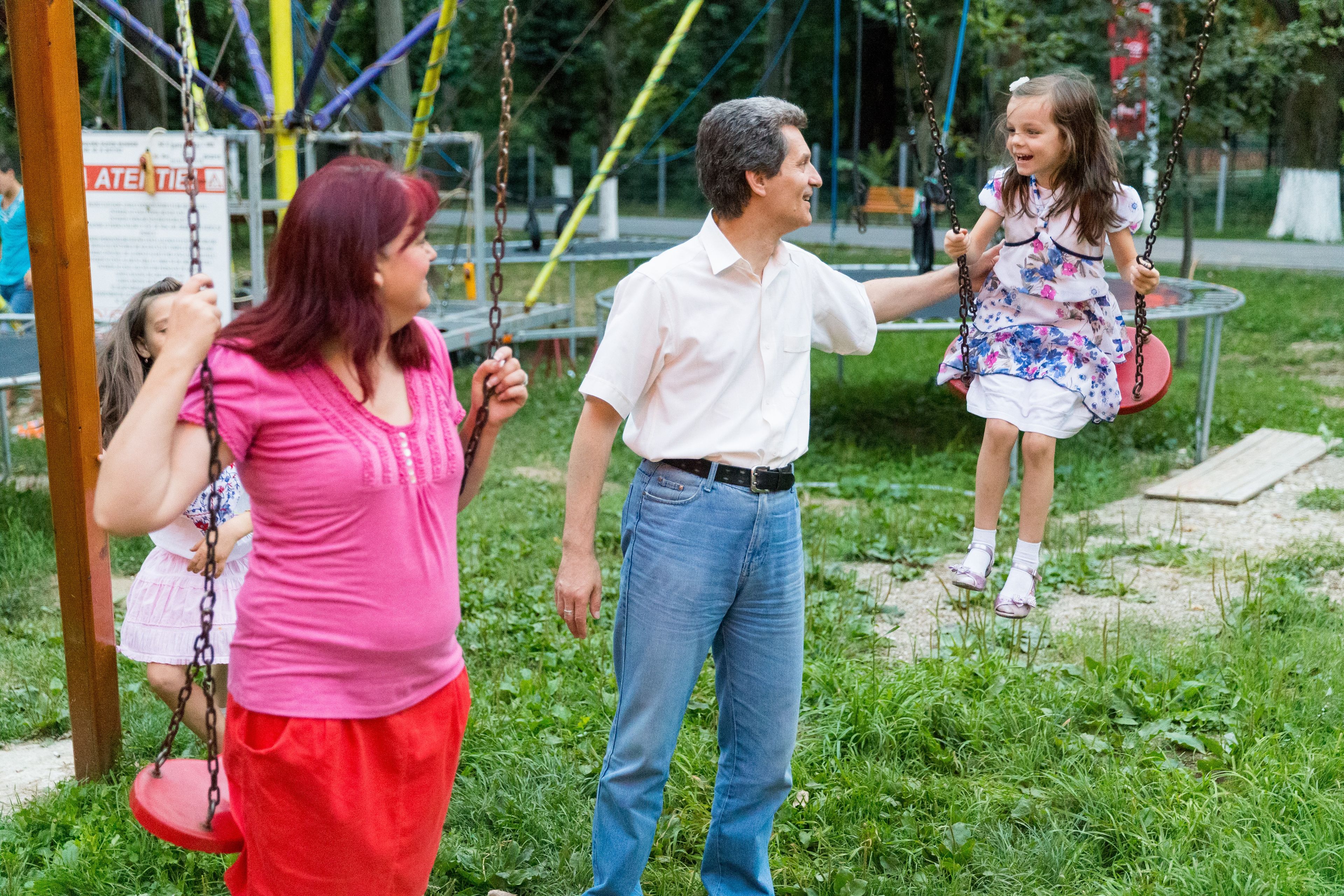 A family in Moldova playing on the swings together.