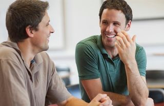 Zwei Männer unterhalten sich und lächeln