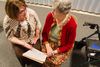 two women talking and looking at notebook