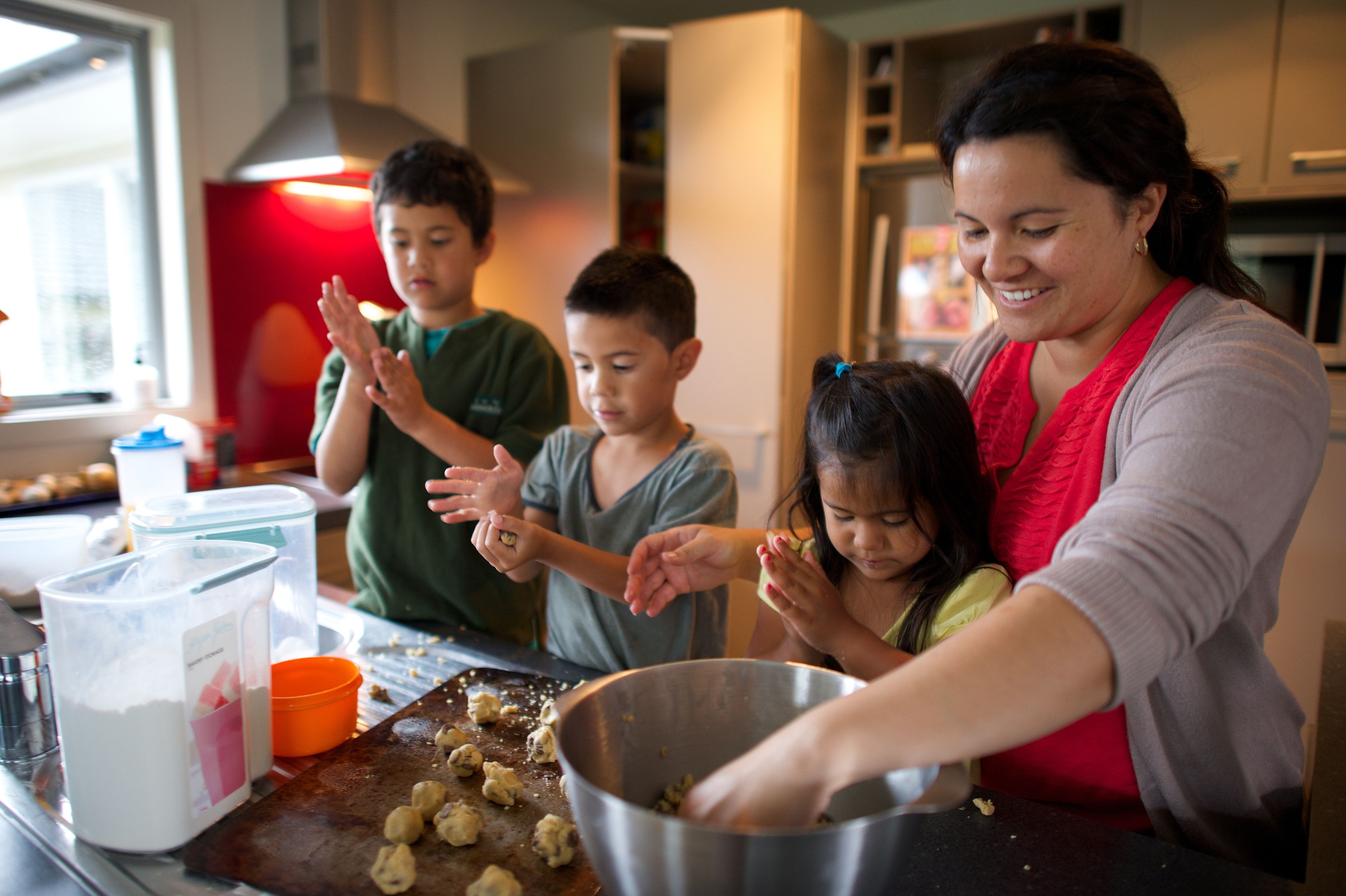 A mother bakes cookies with her children in the kitchen.
