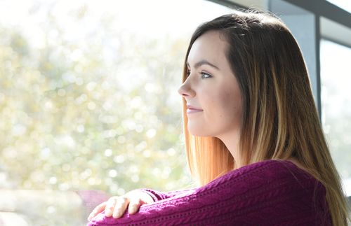 young adult woman looking out window