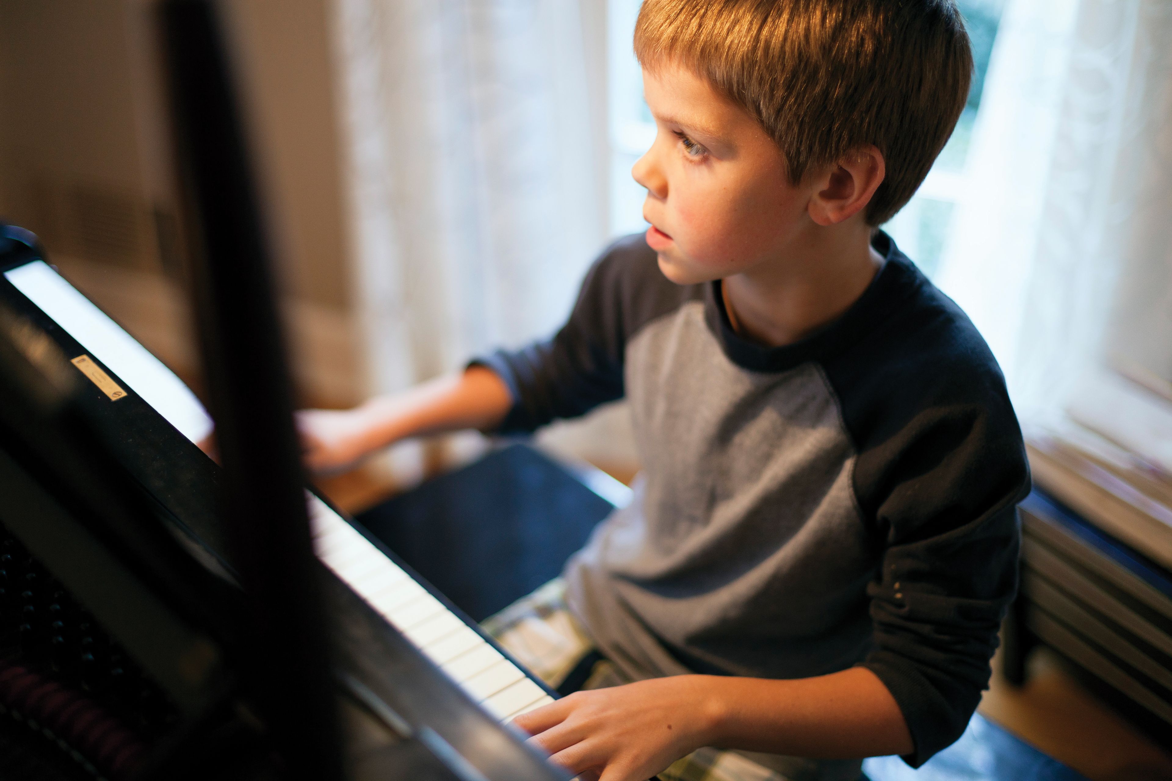 A boy sits down and plays the piano.