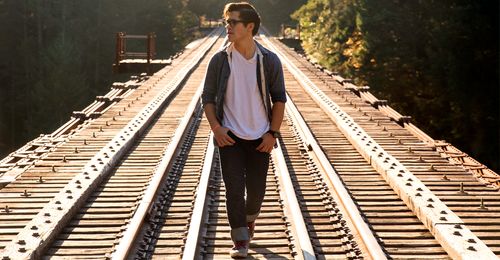 young man walking on railroad