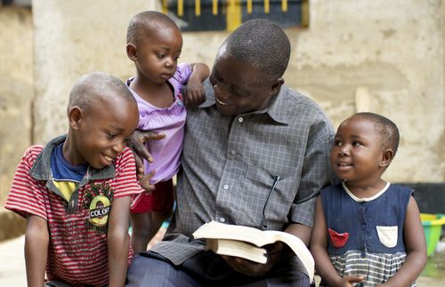 father reading scriptures to his children