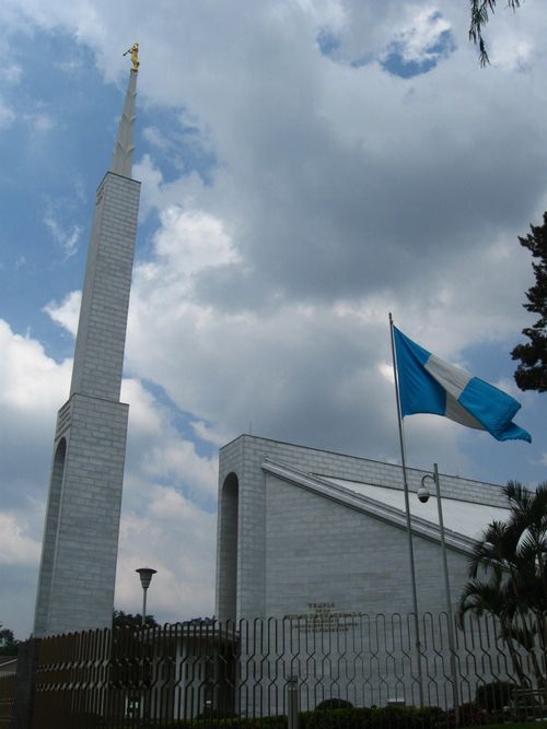 A view of the spire near the Guatemala City Guatemala Temple, with the Guatemalan flag flying in the foreground.