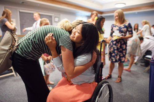 young woman in wheelchair giving hug