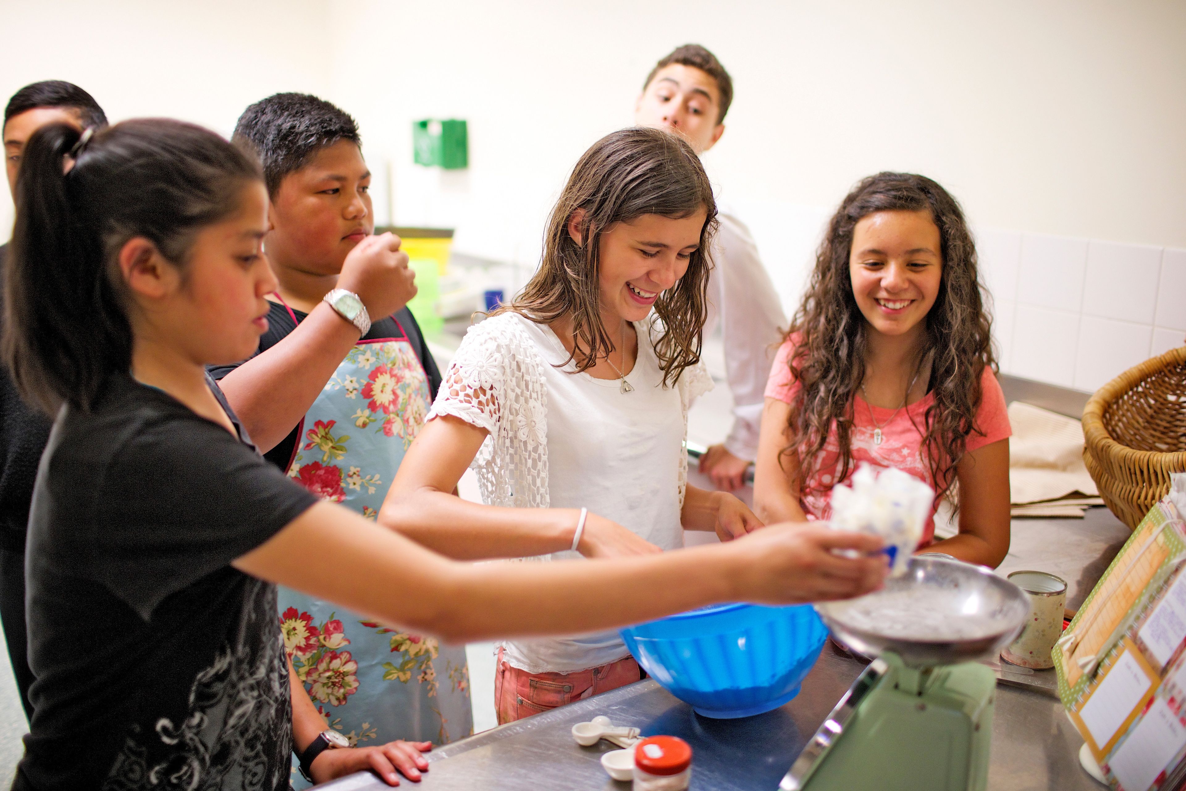 A group of young men and young women bake together for an activity.  
