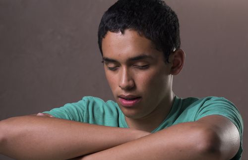 Young man with his eyes closed and arms folded in prayer.