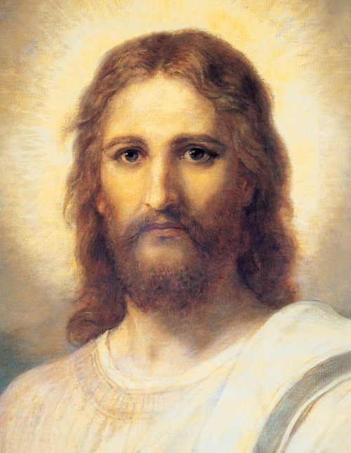 Frontal head and shoulders portrait of Jesus Christ. Christ is depicted wearing a pale red robe with a white and blue shawl over one shoulder. Light emanates from His face.