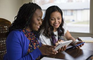 two sister missionaries studying together using a tablet computer