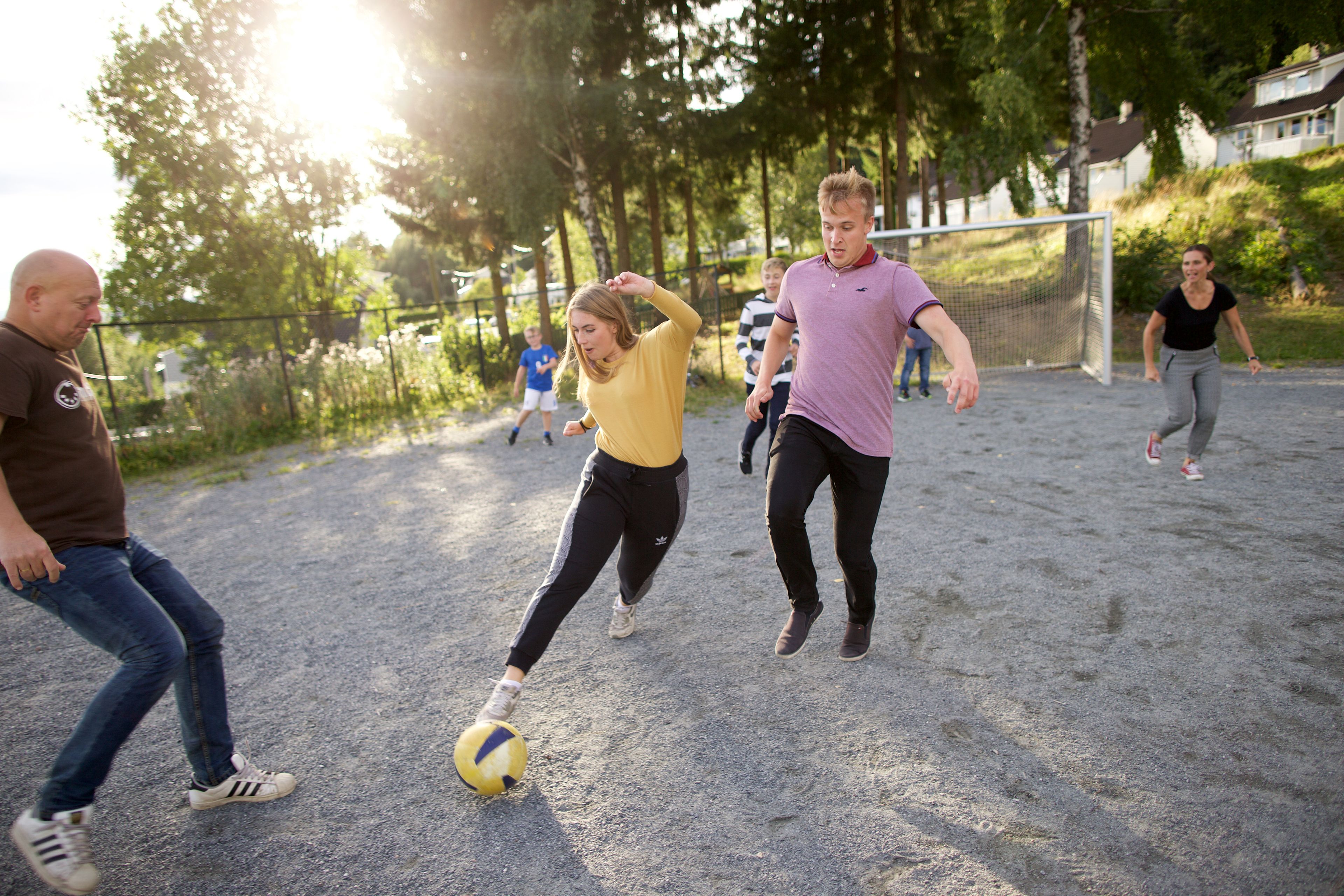 A family in Norway plays soccer together outside their home in the backyard.
