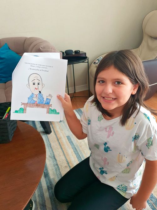 A young girl named Camila holding up her coloring of President Nelson