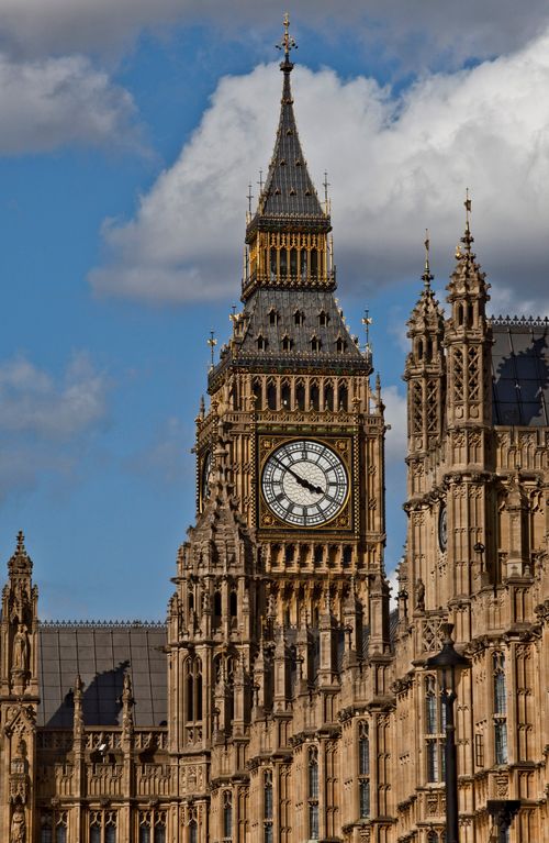 The large white clock of Big Ben, surrounded by other historic buildings in London, England.