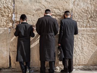 individuals praying at the Western Wall in Jerusalem