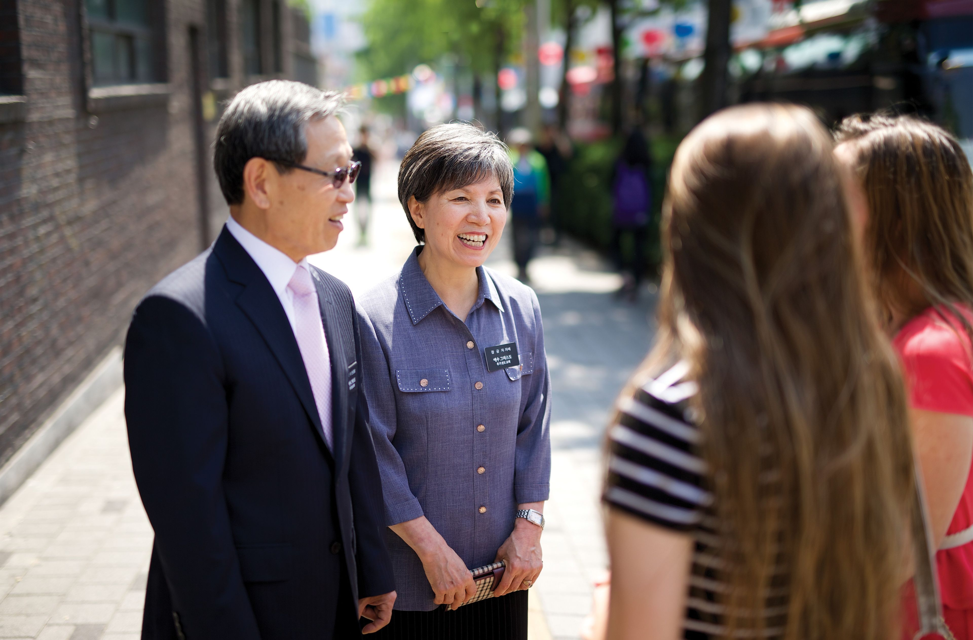 A senior missionary couple talking to people on the streets in Korea.