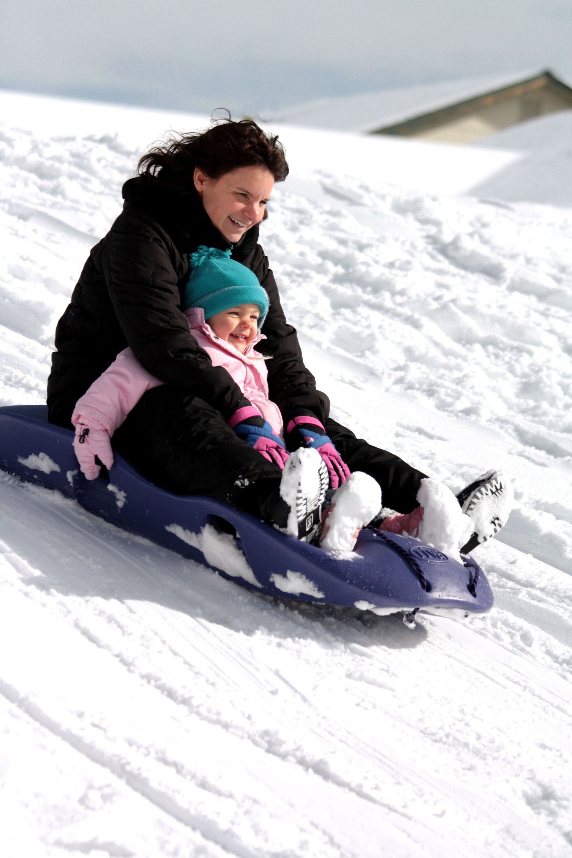 A mother and daughter sled down a hill together.